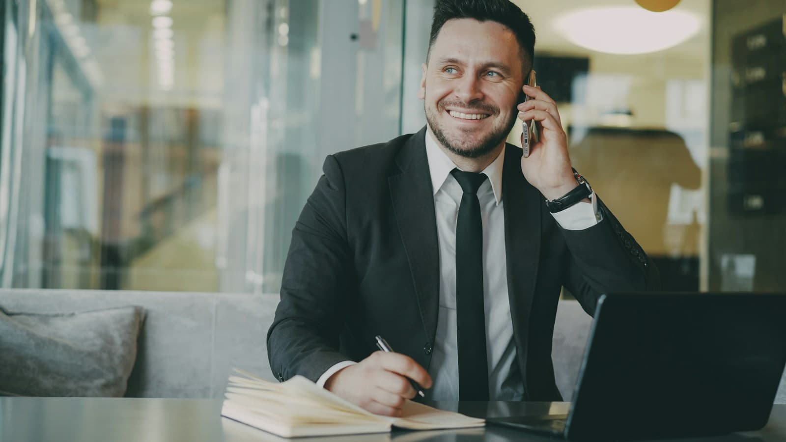 A businessman smiling on a phone call at his desk