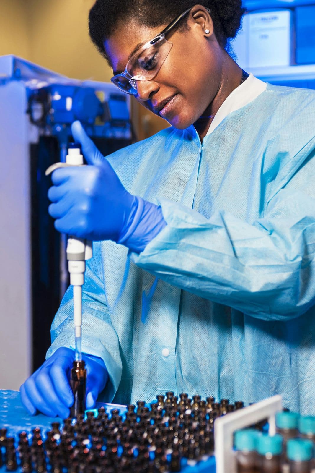 A scientist in protective gear using a pipette in a laboratory