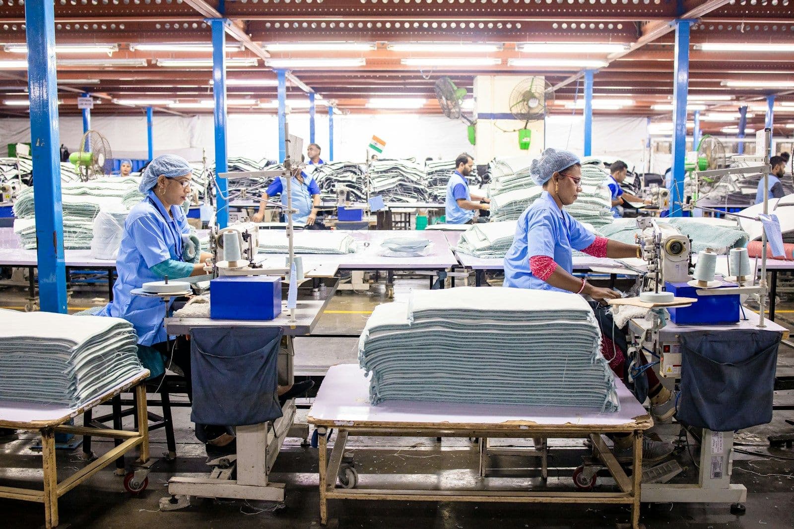 Workers stitching textiles in a large production hall