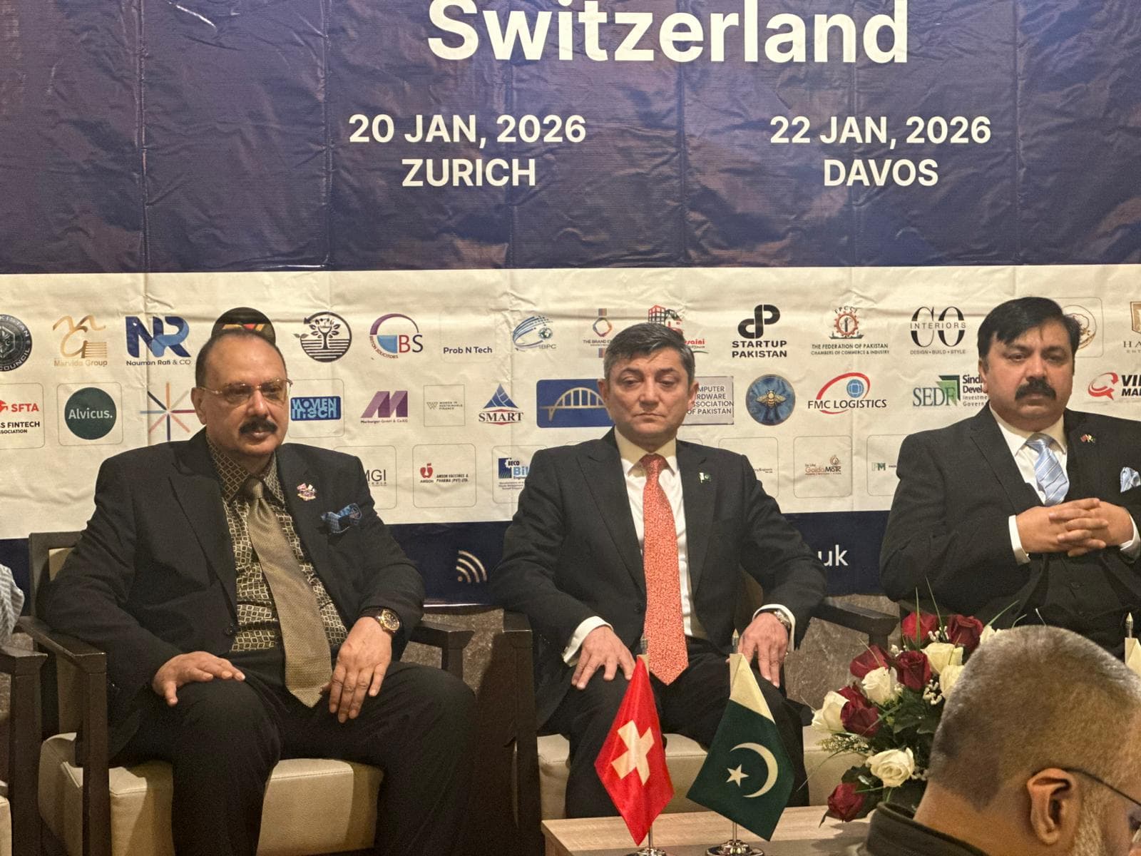 Three panellists seated before the summit backdrop at the 2026 summit