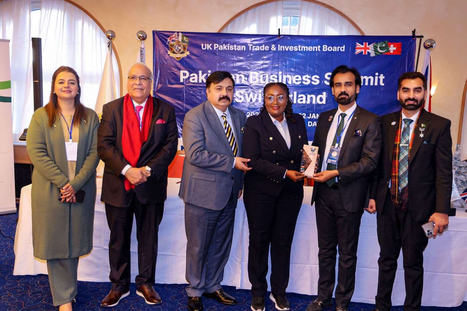 An honoree receiving her award, with the presenters before the summit banner