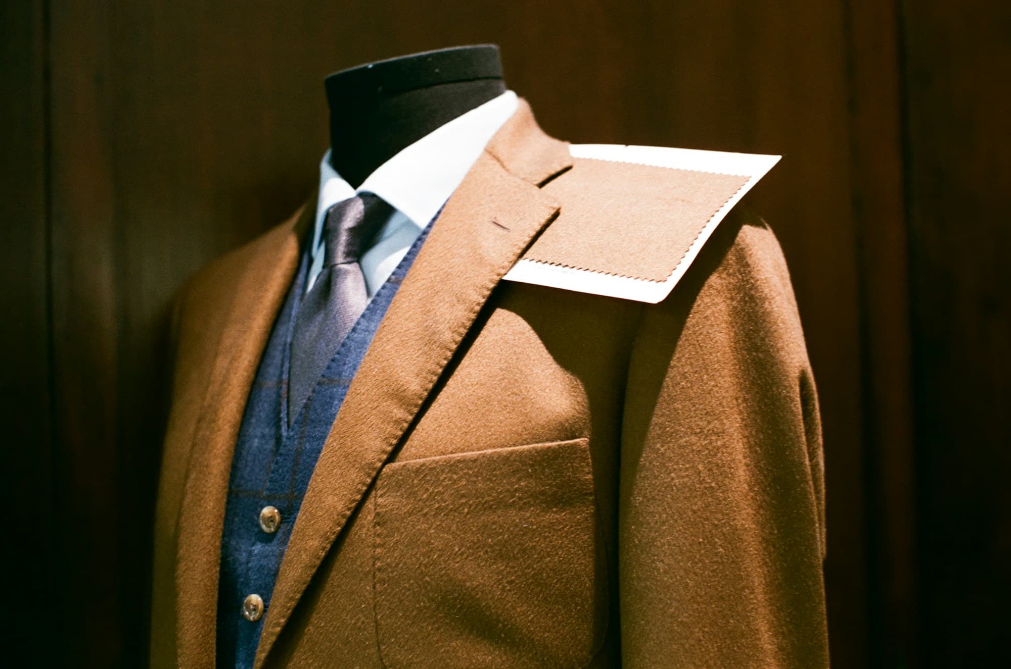 A tailored cashmere jacket with a silk tie on a mannequin in a wood-panelled boutique