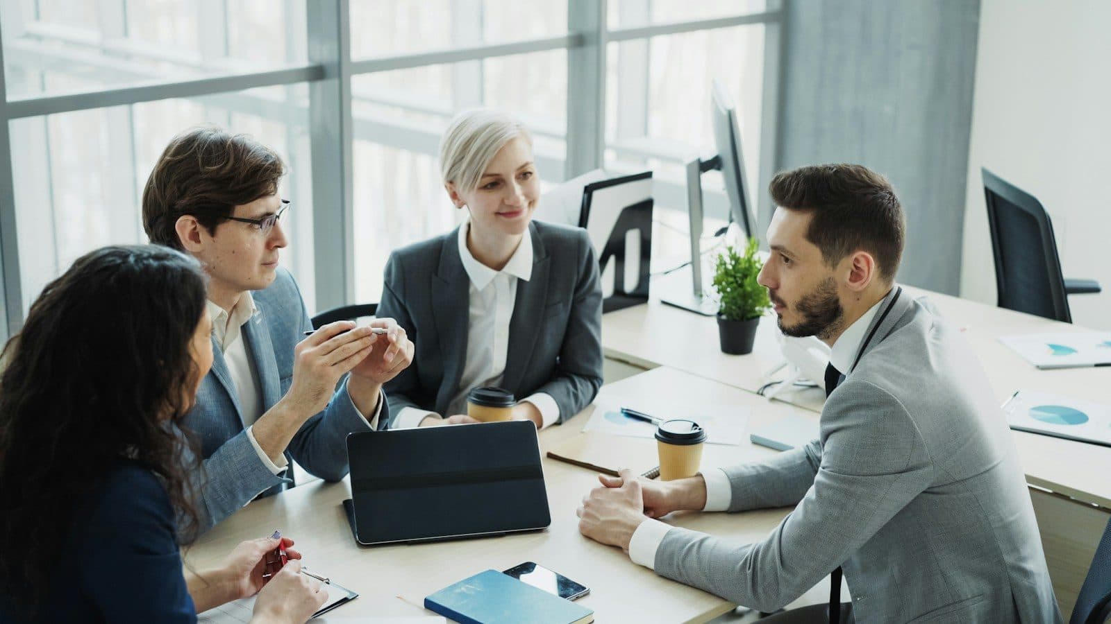 Advisers in discussion around a desk in a bright office